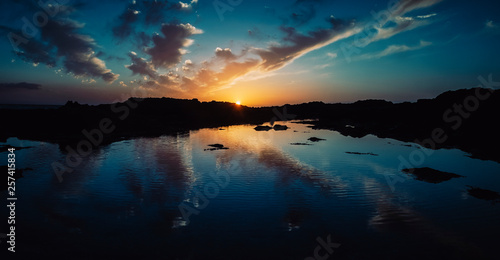 Cold blue tones colors filter for sunrise or sunset at the ocean with clouds and sky mirror on the sea water - evening or early morning nature outdoor vacation concept