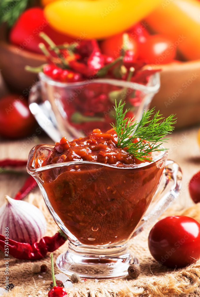 Spicy tomato sauce with pepper and garlic in a glass bowl on the vintage wooden table, selective focus Spicy tomato sauce with pepper and garlic in a glass bowl on the vintage wooden table, selective focus