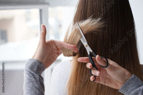 Woman cutting hair of her friend at home