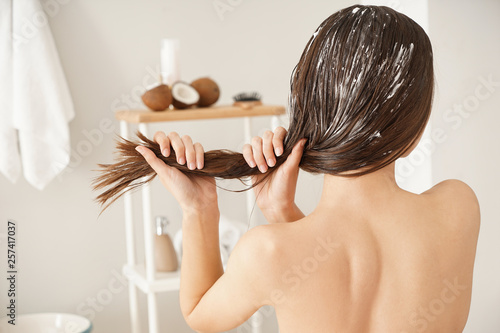 Woman using coconut oil for hair in bathroom photo