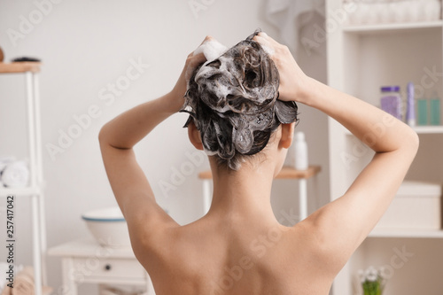 Young woman washing hair in bathroom