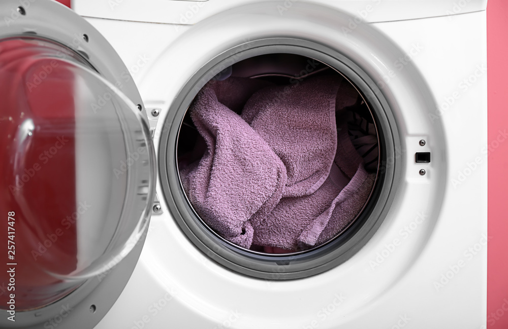 Modern washing machine with laundry on color background Modern washing machine with laundry on color background