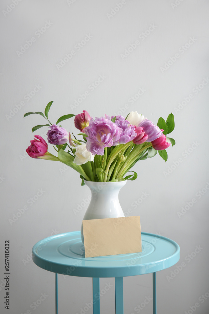Bouquet of beautiful flowers with card on table against grey background Bouquet of beautiful flowers with card on table against grey background