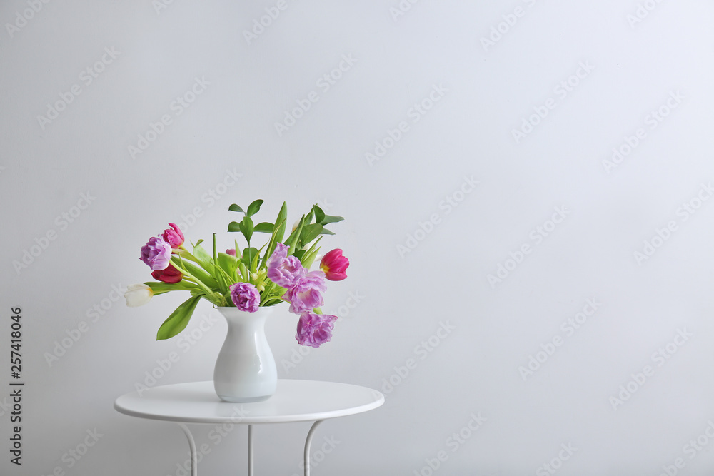 Bouquet of beautiful flowers on table against light background