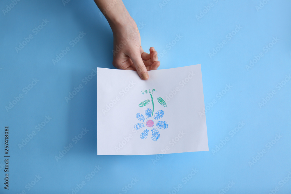 Female hand with picture of beautiful flower on color background Female hand with picture of beautiful flower on color background