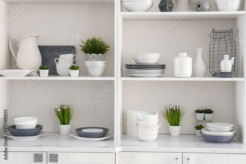 Open cupboard with clean dishes in kitchen