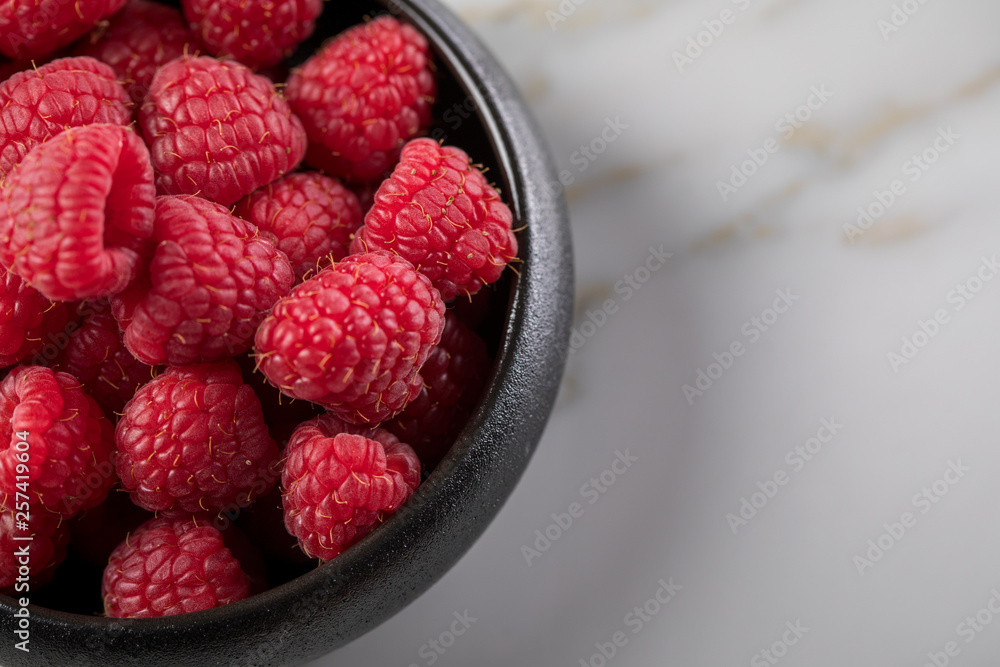 Himbeeren in schwarzer Porzellan Schale auf Marmor Hintergrund Himbeeren in schwarzer Porzellan Schale auf Marmor Hintergrund
