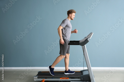 Wallpaper Mural Sporty young man training on treadmill in gym