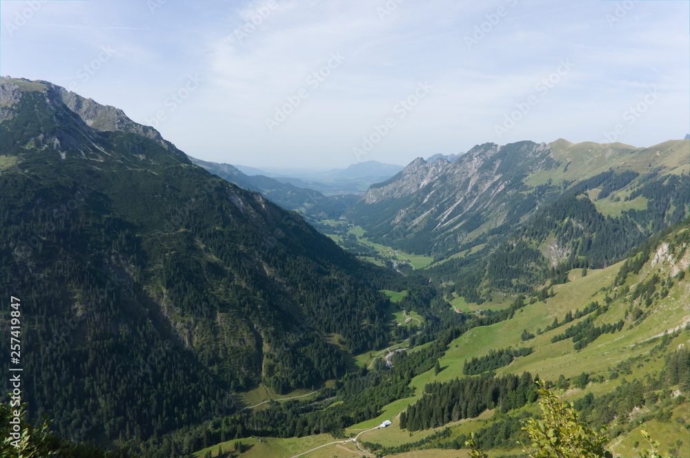 Idyllic summer landscape with hiking trail in the Alps with beautiful fresh green mountain pastures, Allgäu Germany