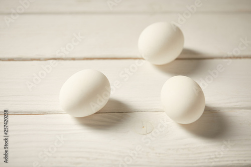selective focus of uncooked chicken eggs on white wooden planks