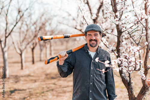 Cheerful gardener holding pruner in backyard. © bnenin