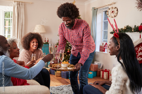 Photography Man Serving Champagne And Snacks As Adult Members Of Family Celebrate Christmas
