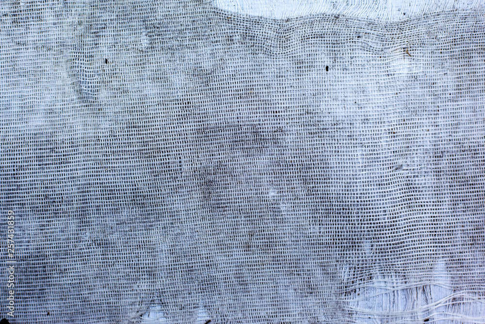 The texture of torn white fabric with a large cage or burlap, curtain, background