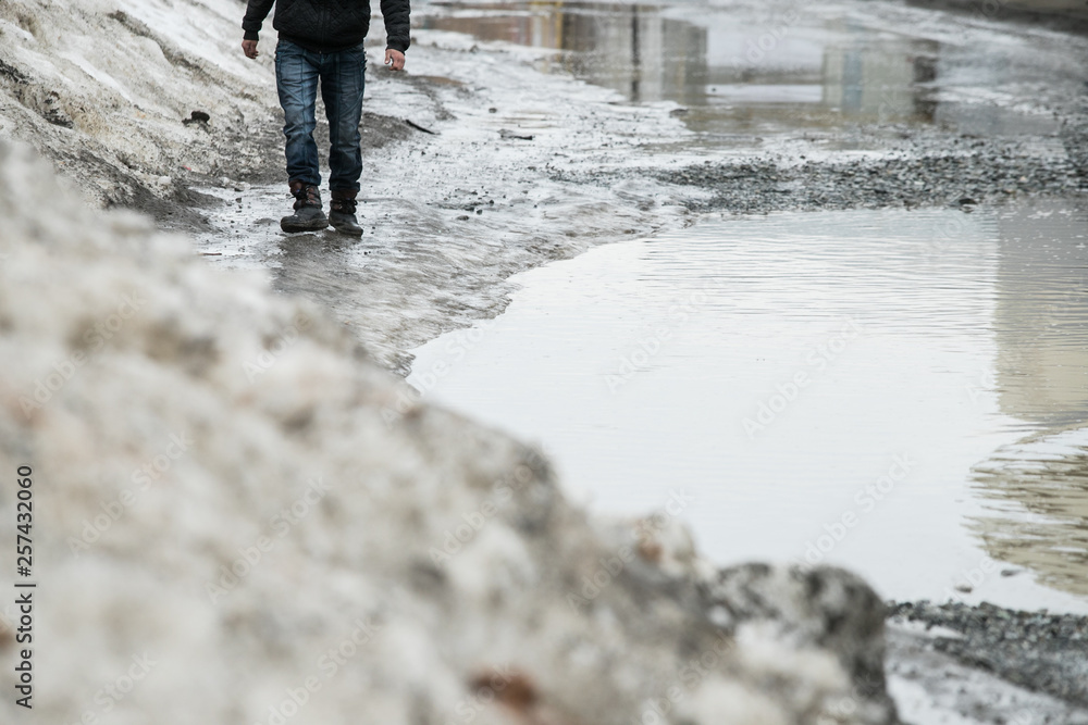 warming in early spring, snow melts turning into slush and puddles underfoot, which bypass the pedestrians walking on the sidewalk and crossing the road with wet feet warming in early spring, snow melts turning into slush and puddles underfoot, which bypass the pedestrians walking on the sidewalk and crossing the road with wet feet