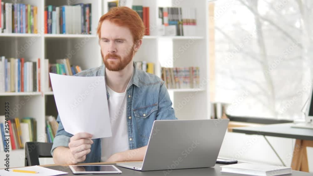 Casual Redhead Man Reading Contract at Work Casual Redhead Man Reading Contract at Work