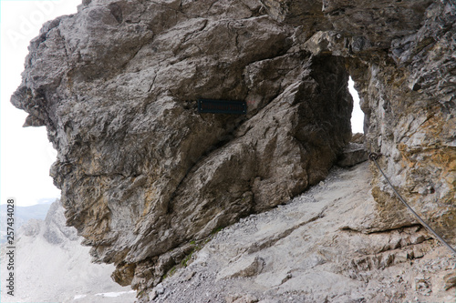 Hiking throug a hole  gap in a rock  in the european alps