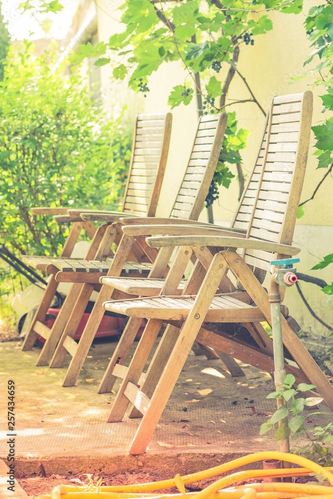 Two old fashioned wooden chair in a garden colored effect with sunlight