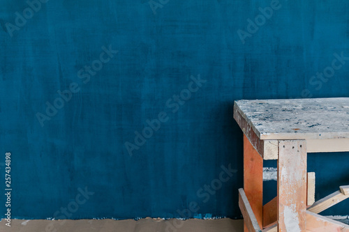 Concept Of Repair in The House  Freshly Painted Blue Wall With Plaster Texture. Wooden Platform On Foreground  copy space.