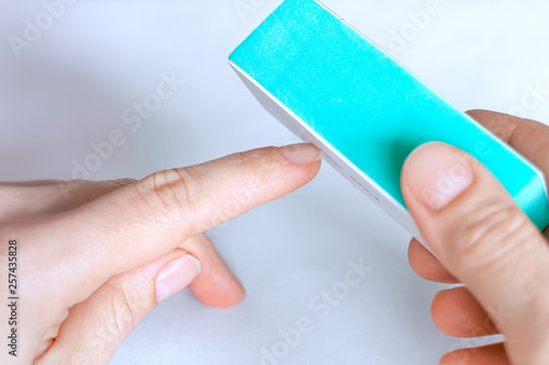 Woman buffing natural unpainted nails with nail buffer.
