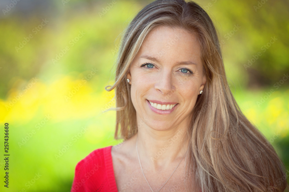 Portrait Of A Middle aged woman Smiling at the camera. She is standing at the park	