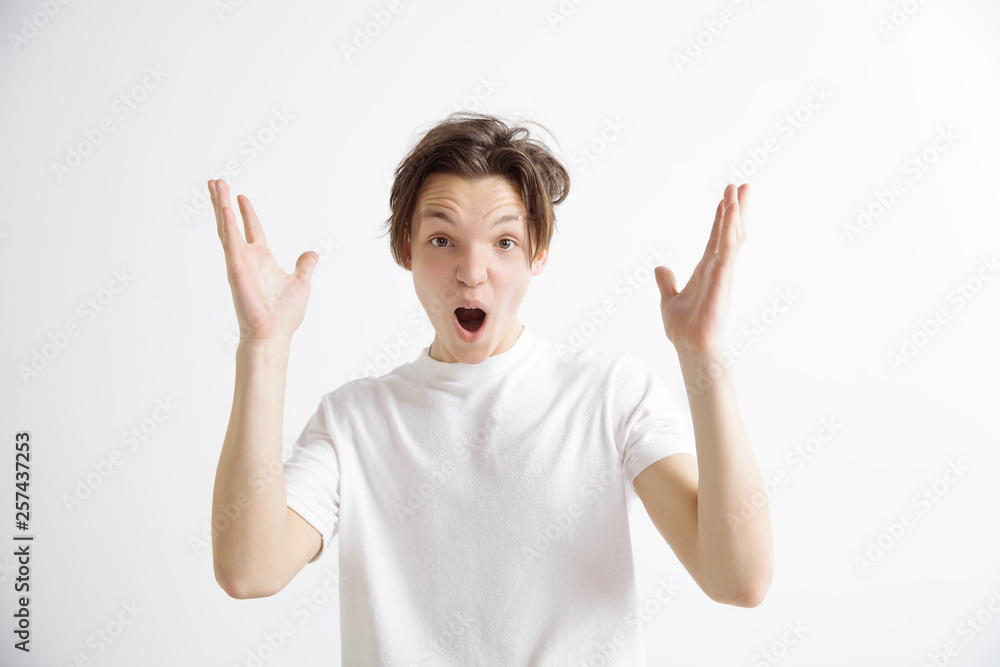 Wow. Attractive male half-length front portrait on gray studio backgroud. Young emotional surprised man standing with open mouth. Human emotions, facial expression concept Wow. Attractive male half-length front portrait on gray studio backgroud. Young emotional surprised man standing with open mouth. Human emotions, facial expression concept