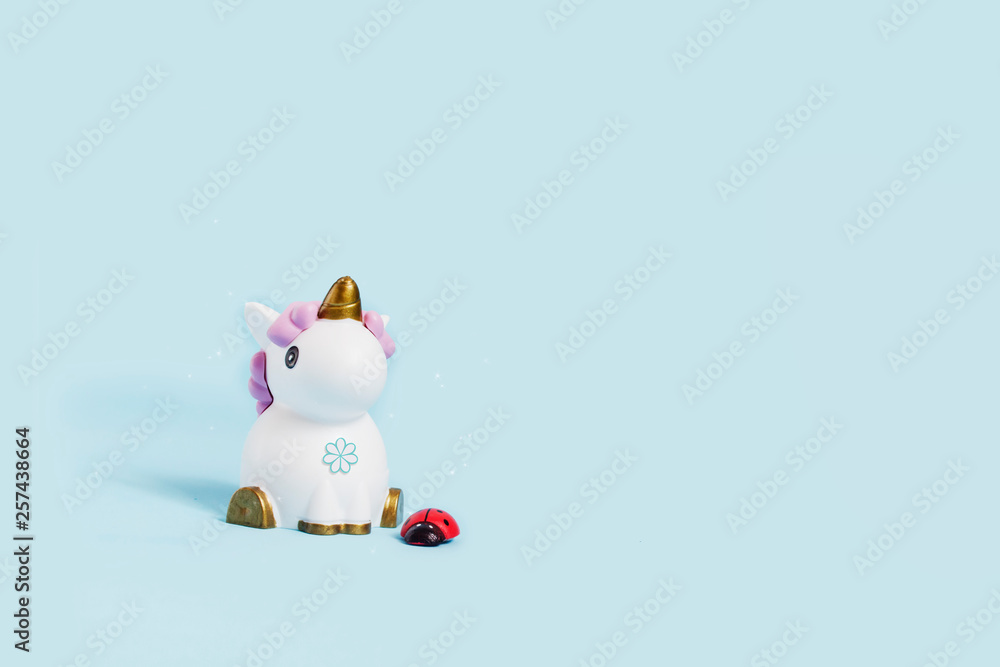 white toy unicorn and ladybug on a blue background