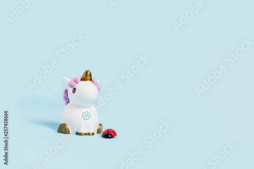 white toy unicorn and ladybug on a blue background