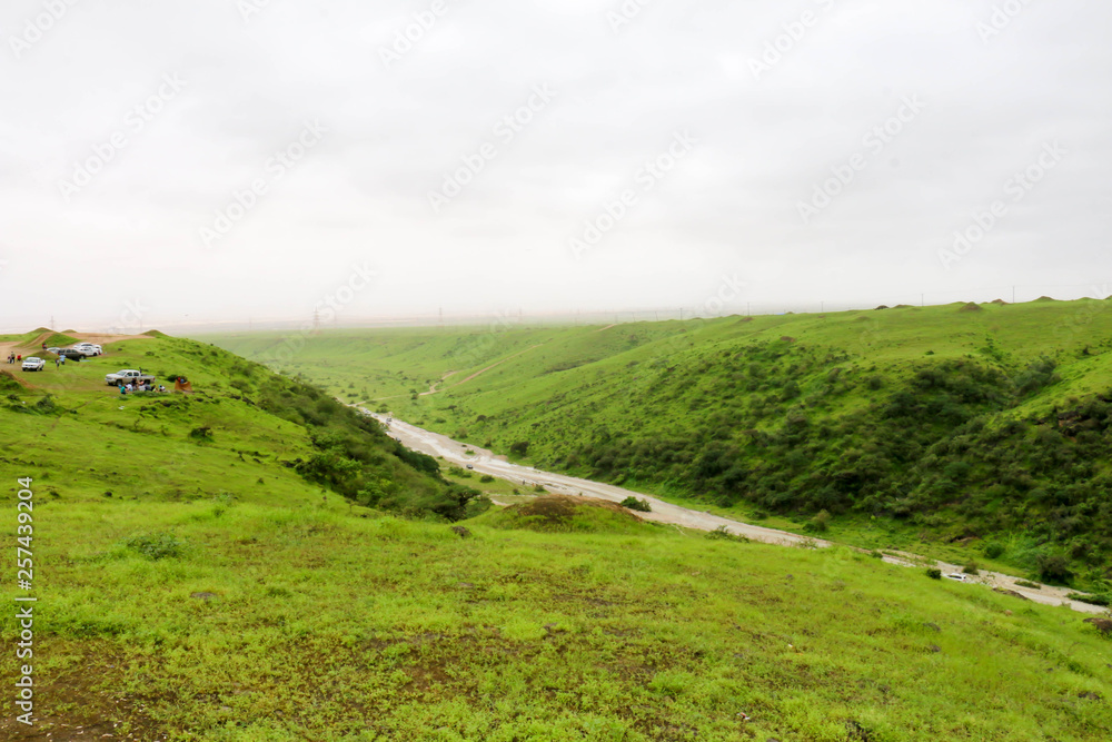 Lush green landscape, trees and foggy mountains in Ayn Khor tourist resort, Salalah, Oman Lush green landscape, trees and foggy mountains in Ayn Khor tourist resort, Salalah, Oman