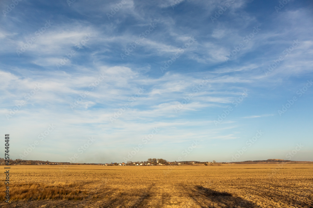 view of a large field and the village on the horizon during sunset