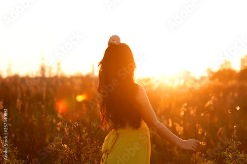 Young charming girl with a gorgeous shiny hair looks at beautiful sunset. Closeup portrait