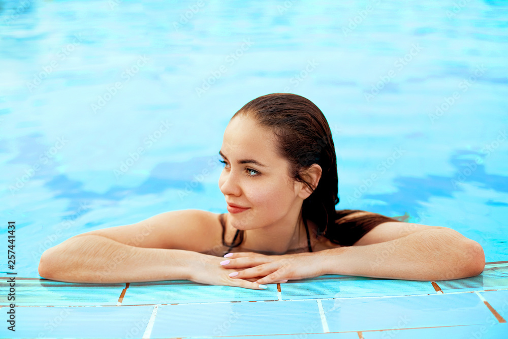Beautiful Sexy Woman Relaxing In Swimming Pool Water. Girl With Healthy Tanned Skin, Gorgeous Face, Fashion Makeup And Wet Hair Enjoying Summer Sun On Hot Summer Day At Pool Edge At Luxury Resort Beautiful Sexy Woman Relaxing In Swimming Pool Water. Girl With Healthy Tanned Skin, Gorgeous Face, Fashion Makeup And Wet Hair Enjoying Summer Sun On Hot Summer Day At Pool Edge At Luxury Resort