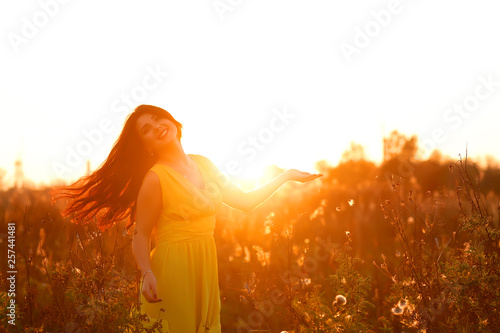 portrait of beautiful young adult woman in the sunlight at sunset. Pretty girl is smiling. She is cute and funny. Beautiful woman is enjoying warm and sunlight. She is basking in the sun