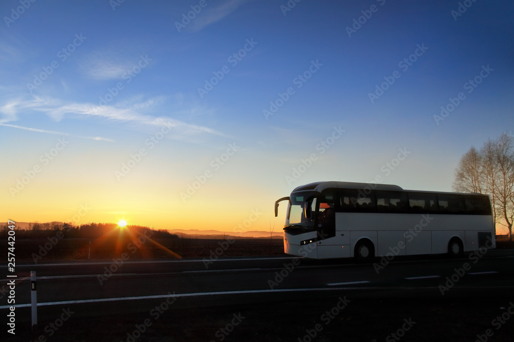 White bus  on the road at sunset carrying tourists on vacation