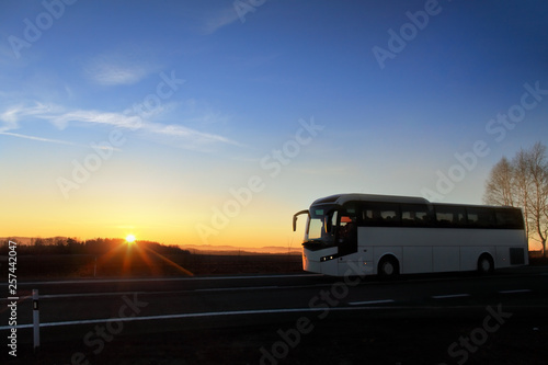 White bus on the road at sunset carrying tourists on vacation