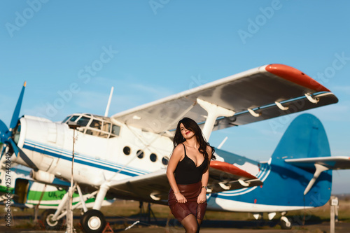 Airplane and woman at sunset. Summer funny secular girl standing at airplane. Woman and landing commercial plane in the evening. Lifestyle photo