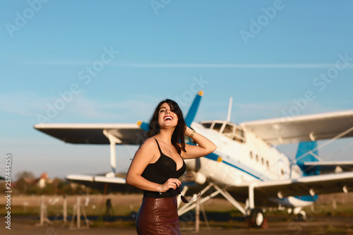 Funny girl portrain standing at airplane. Airplane and woman at sunset. Woman and landing commercial plane in the evening. Lifestyle