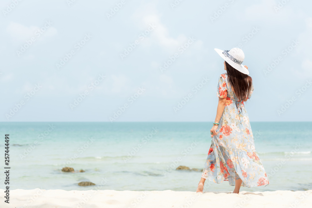 Summer Holiday. Lifestyle woman wearing fashion summer trips standing on the sandy ocean beach. Happy woman enjoy and relax vacation. Lifestyle and Travel Concept Summer Holiday. Lifestyle woman wearing fashion summer trips standing on the sandy ocean beach. Happy woman enjoy and relax vacation. Lifestyle and Travel Concept