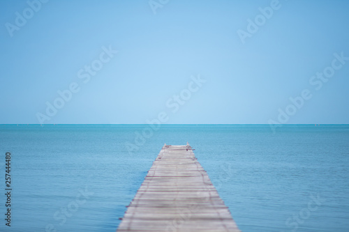 long wooden bridge on the sea with blue sky at sunny day. soft focus.
