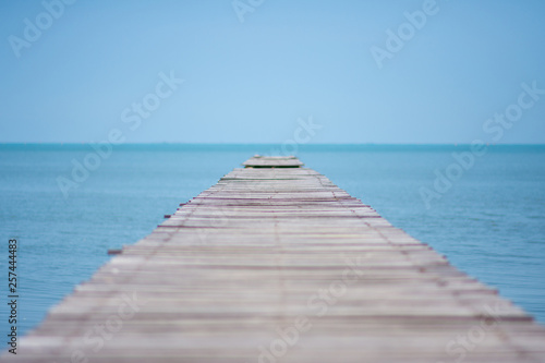 long wooden bridge on the sea with blue sky at sunny day. soft focus.