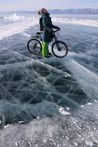 Girl with a bicycle in iced Baikal lake