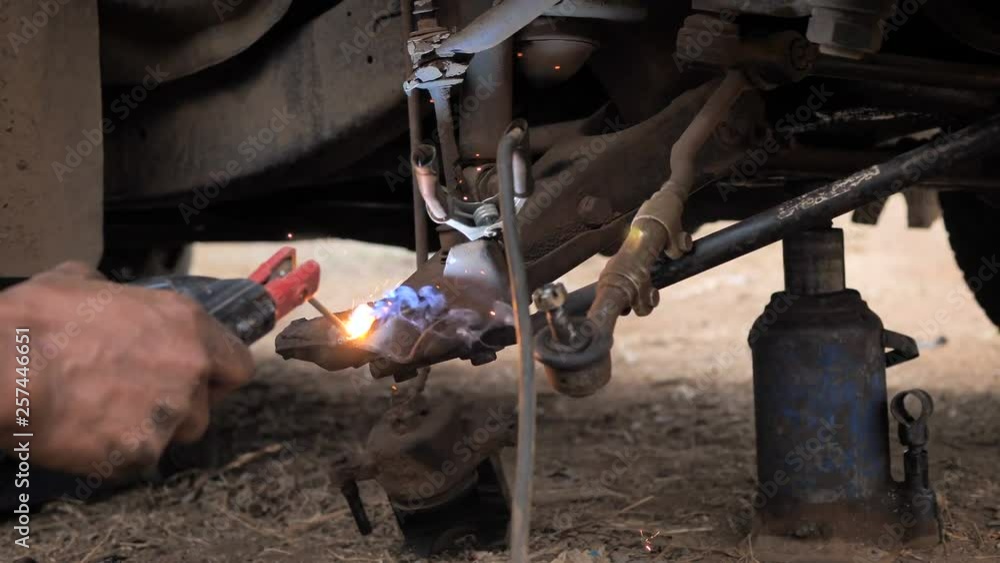 Hands of mechanic welding for repair the truck wishbone control arm of front wheel Hands of mechanic welding for repair the truck wishbone control arm of front wheel