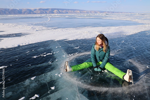 Girl with skates lying on ice of Baikal lake