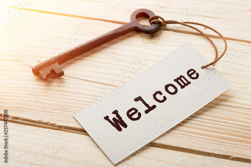 VIntage hotel key with welcome tag on the wooden background