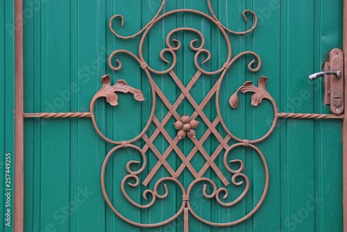 background of metal from iron rods in a forged pattern on the green wall of the fence