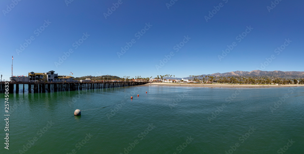 Santa  Barbara pier under blue sky with panoramic view of scenic beach with palm trees