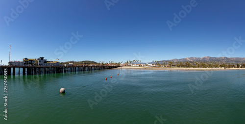 Santa  Barbara pier under blue sky with panoramic view of scenic beach with palm trees