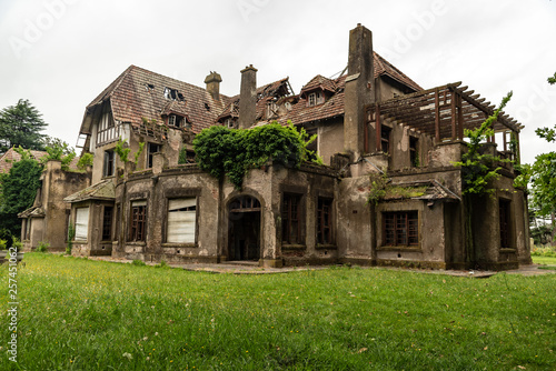 Old abandoned house that caught fire with a green garden and a clouded sky