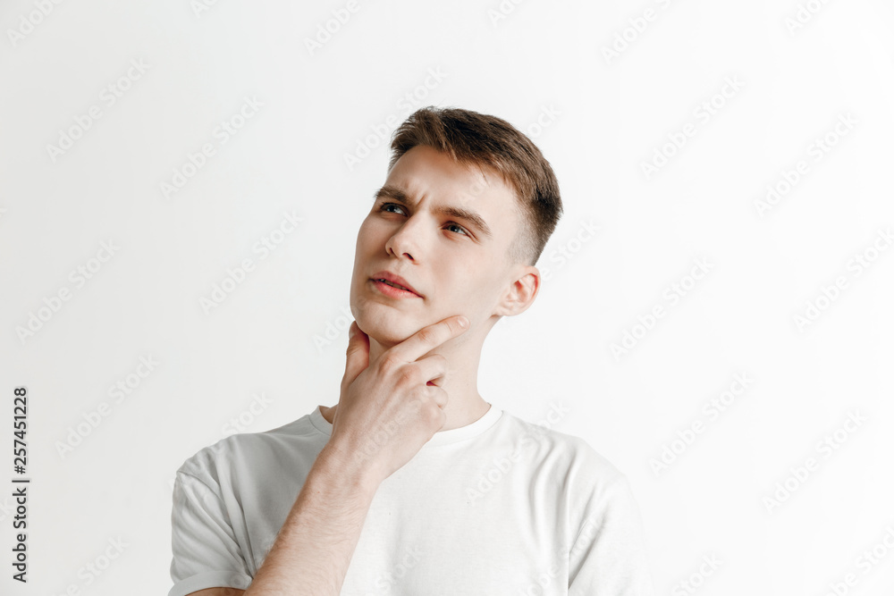 Looking for the best moment. Young dreaming smiling man is waiting for chanses isolated on gray background. Dreamer at studio in white T-shirt Looking for the best moment. Young dreaming smiling man is waiting for chanses isolated on gray background. Dreamer at studio in white T-shirt