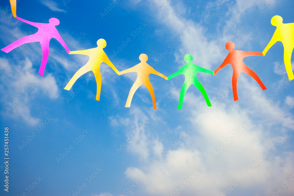 Multi coloured paper dolls against a blue sky Multi coloured paper dolls against a blue sky
