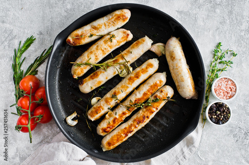 Fried sausages in a frying pan. Gray background, top view